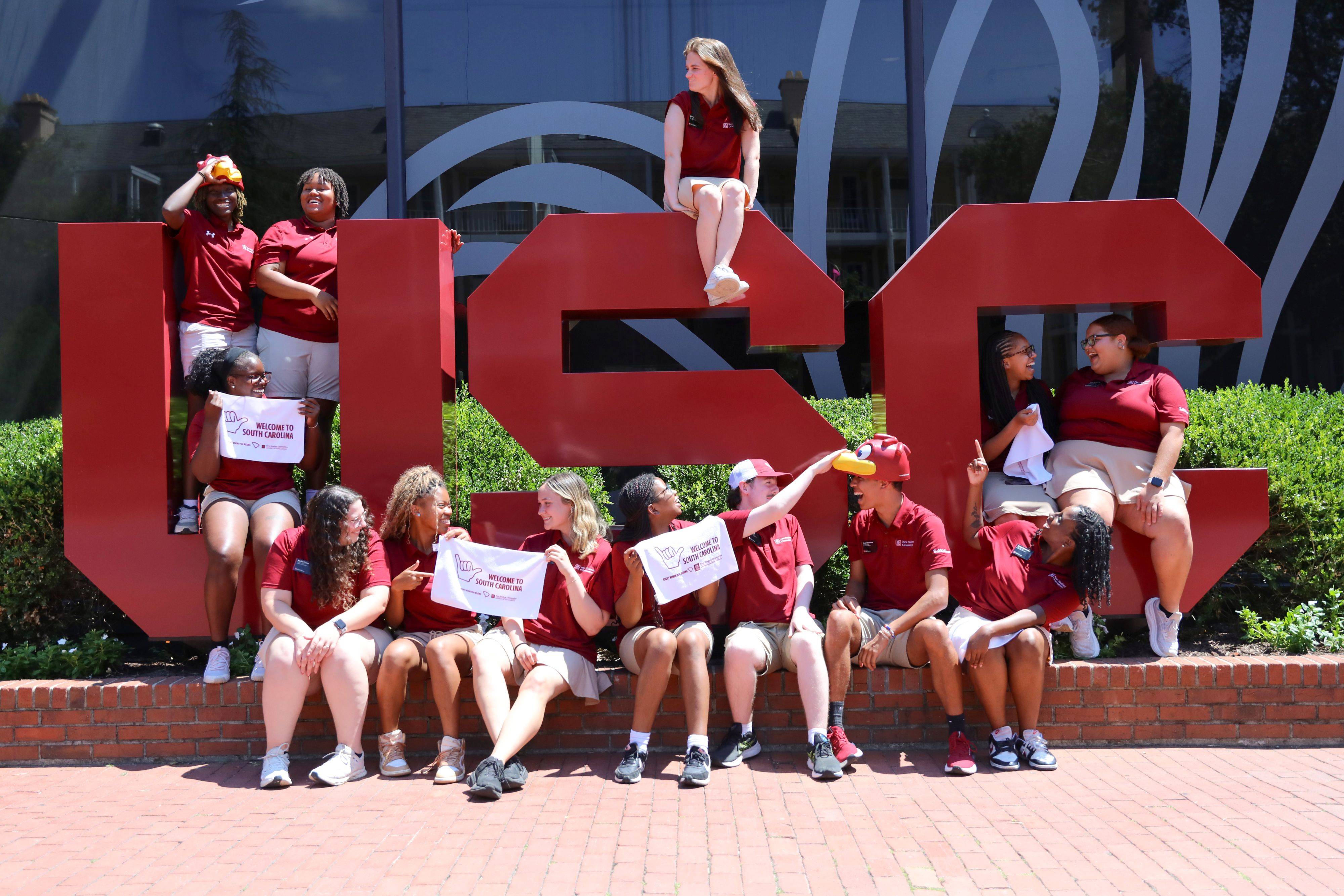 Orientation leaders sitting for a picture with the USC letters in front of the student union.