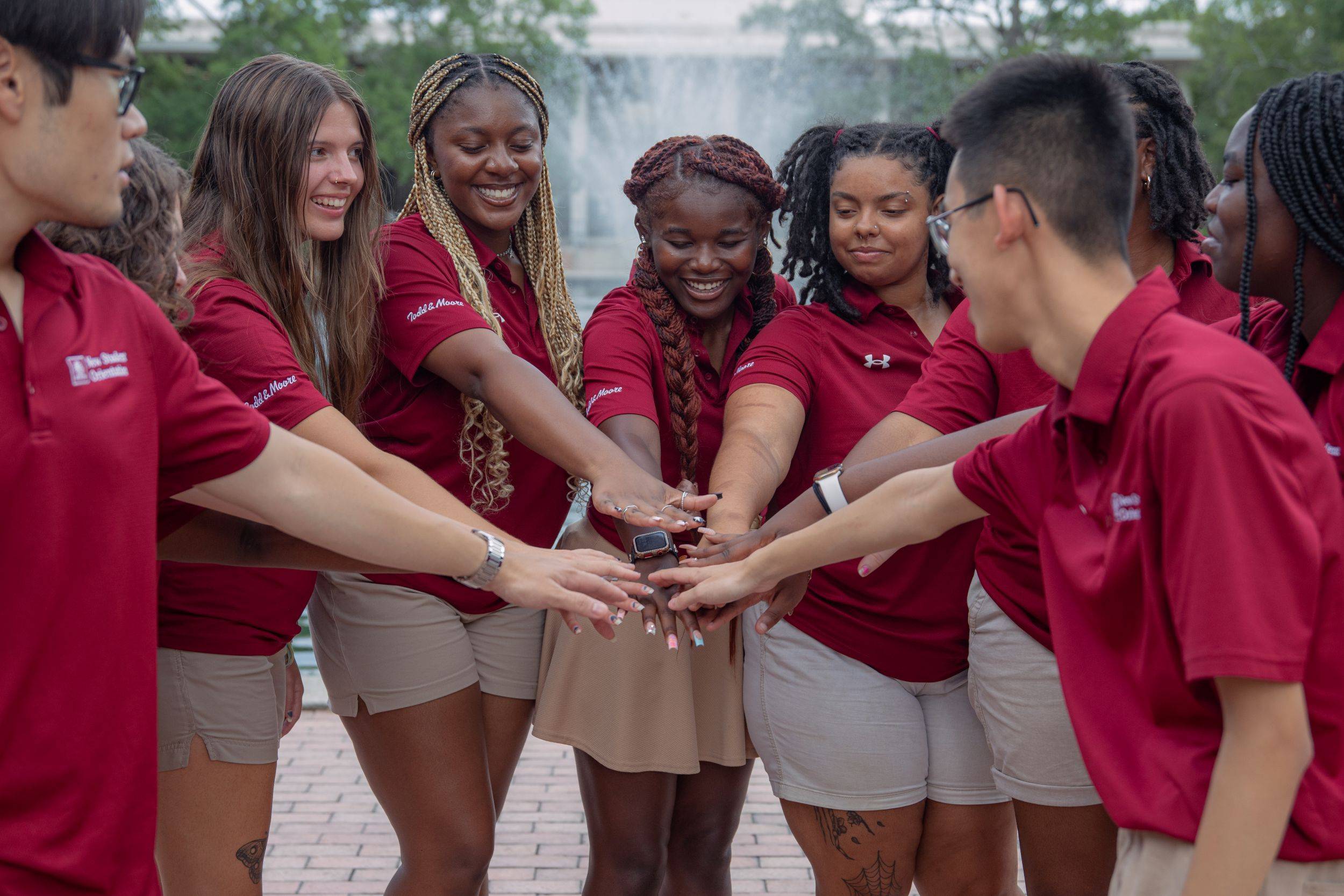 Orientation leaders putting their hands in a circle for a cheer.