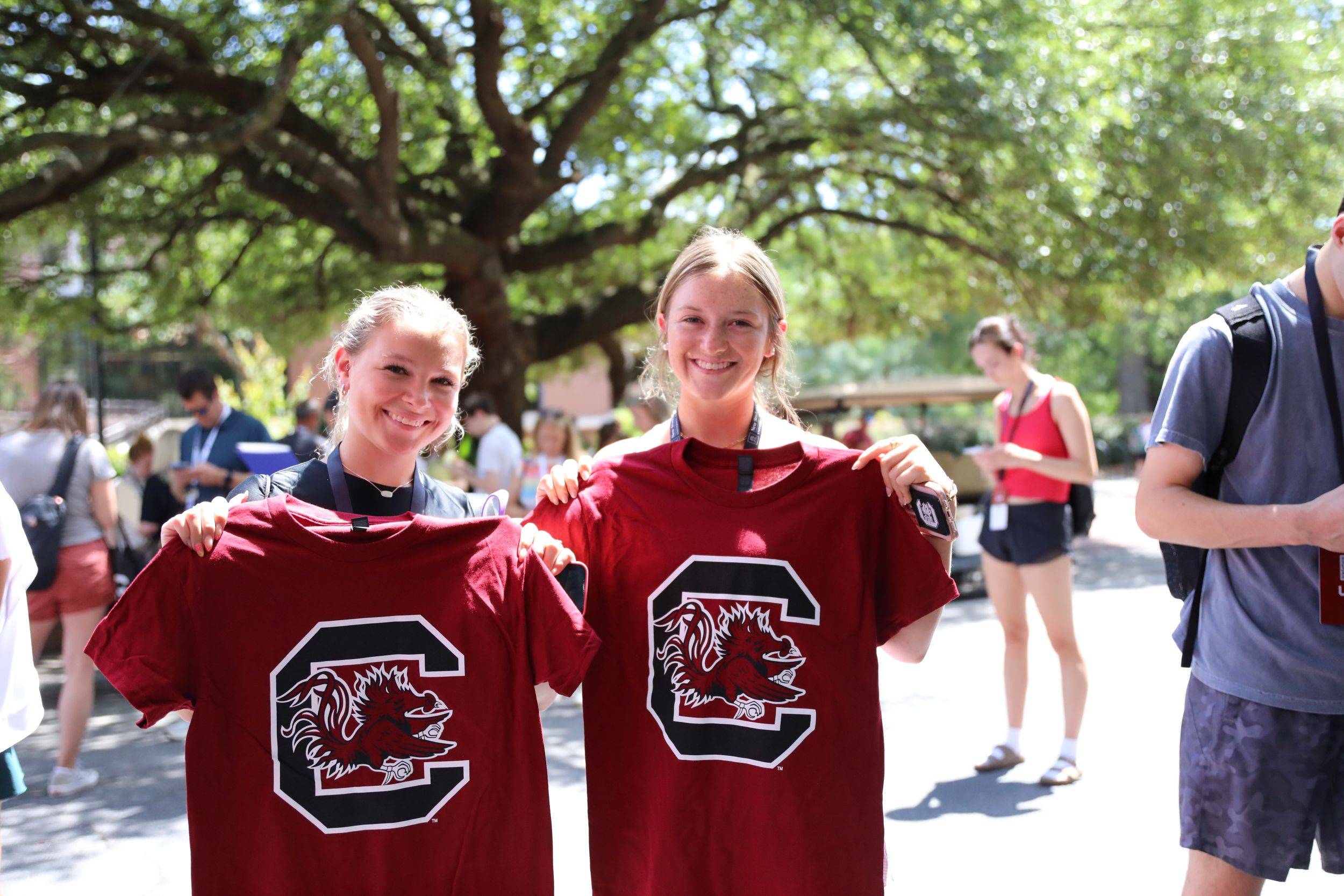 Two students holding up garnet t-shirts with the gamecock logo.