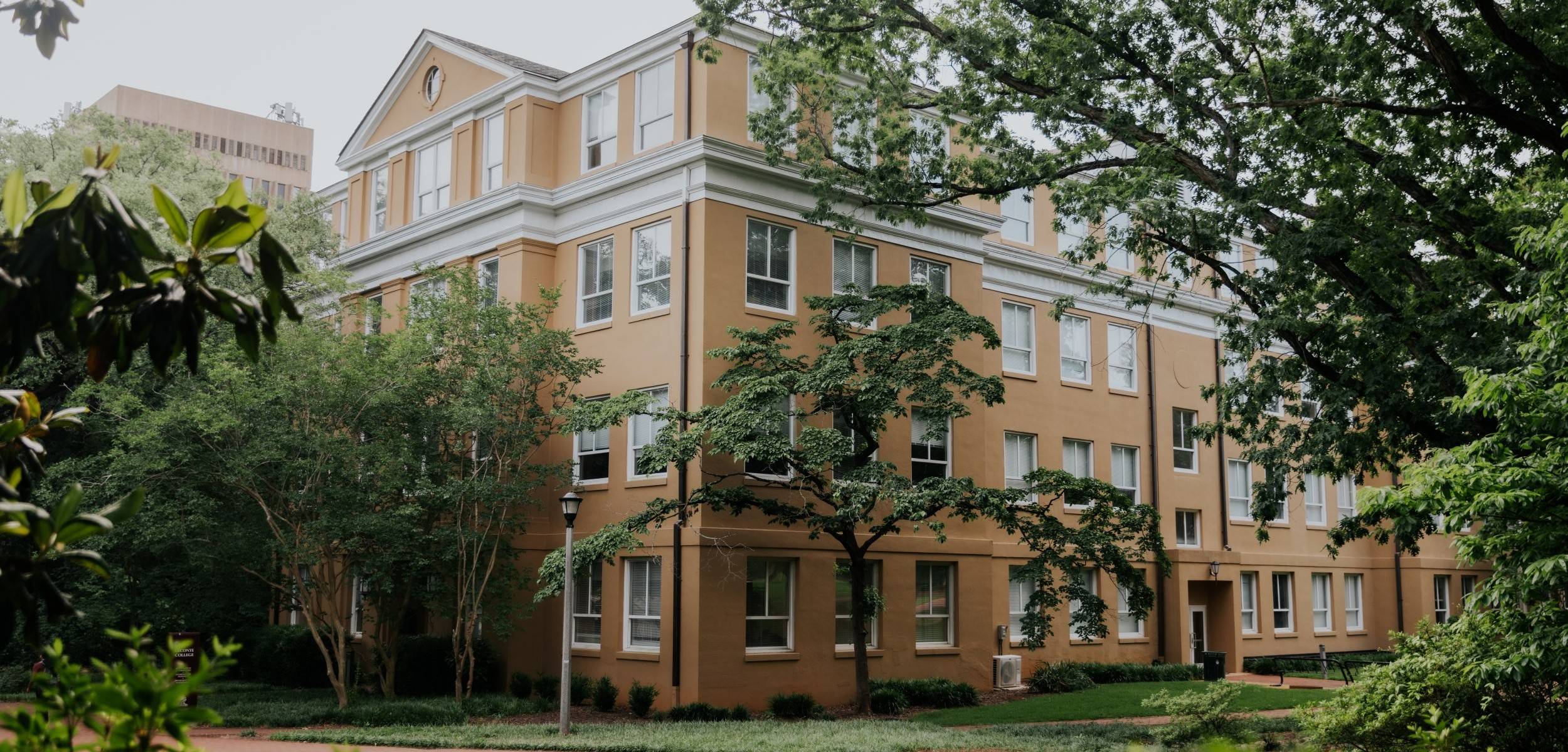 Orange brick building surrounded by green trees and manicured lawn