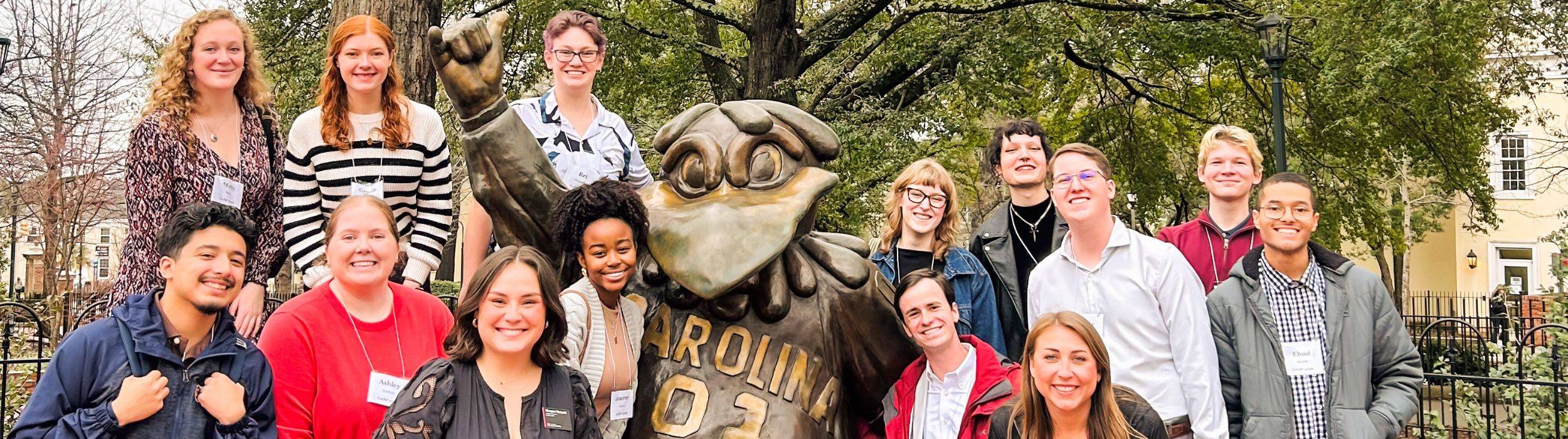 Graduate students in front of a statue of a man on a horse 