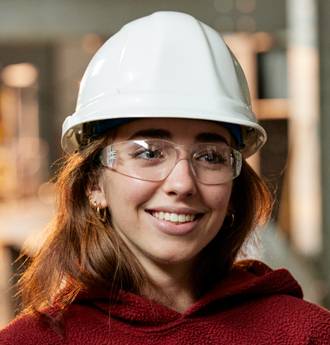 Young person wearing white hard hat and safety glasses