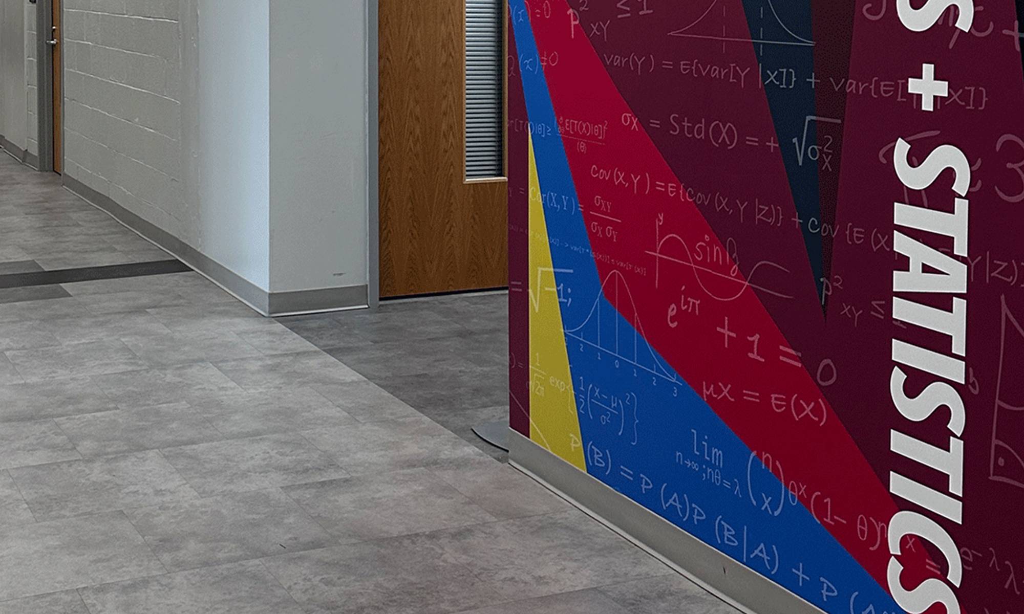 Colorful hallway panel displaying statistical formulas next to a lecture announcement banner.