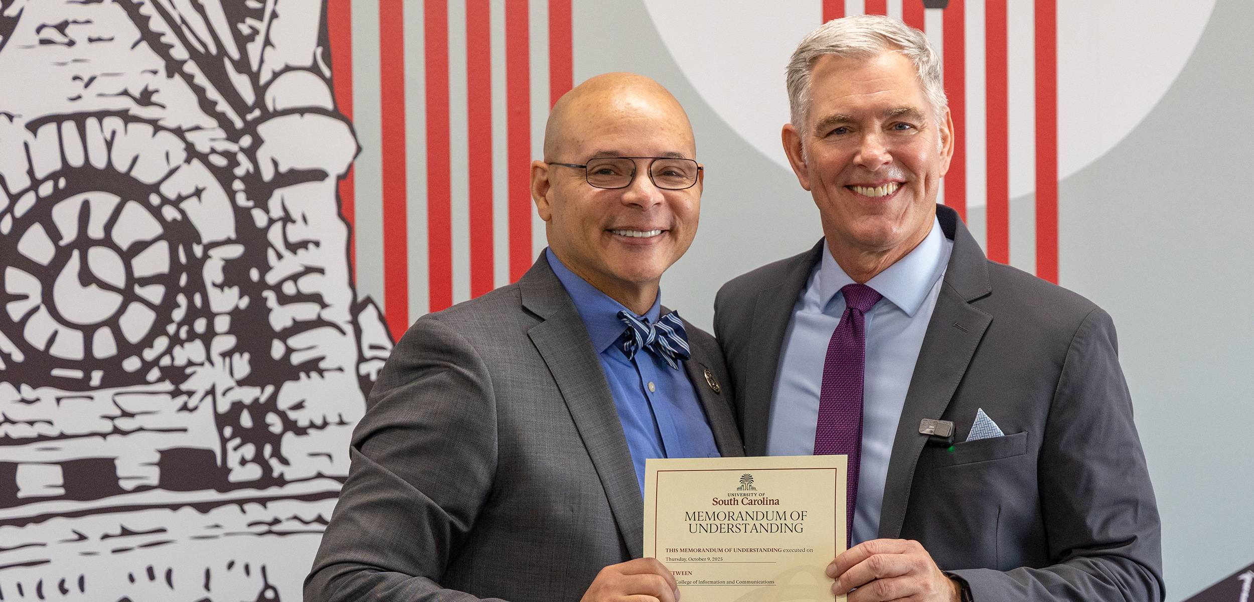 The two deans holding a Memorandum of Understanding