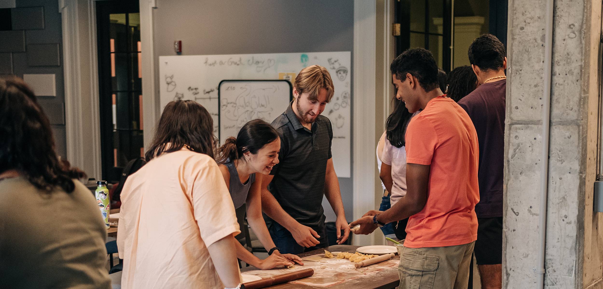 Students smiling as they make dumplings by hand.