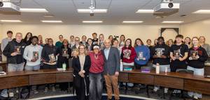 University of South Carolina women's basketball coach Dawn Staley poses with College of Hospitality, Retail and Sport Management students, faculty and staff in a classroom with many students holding copies of her book.
