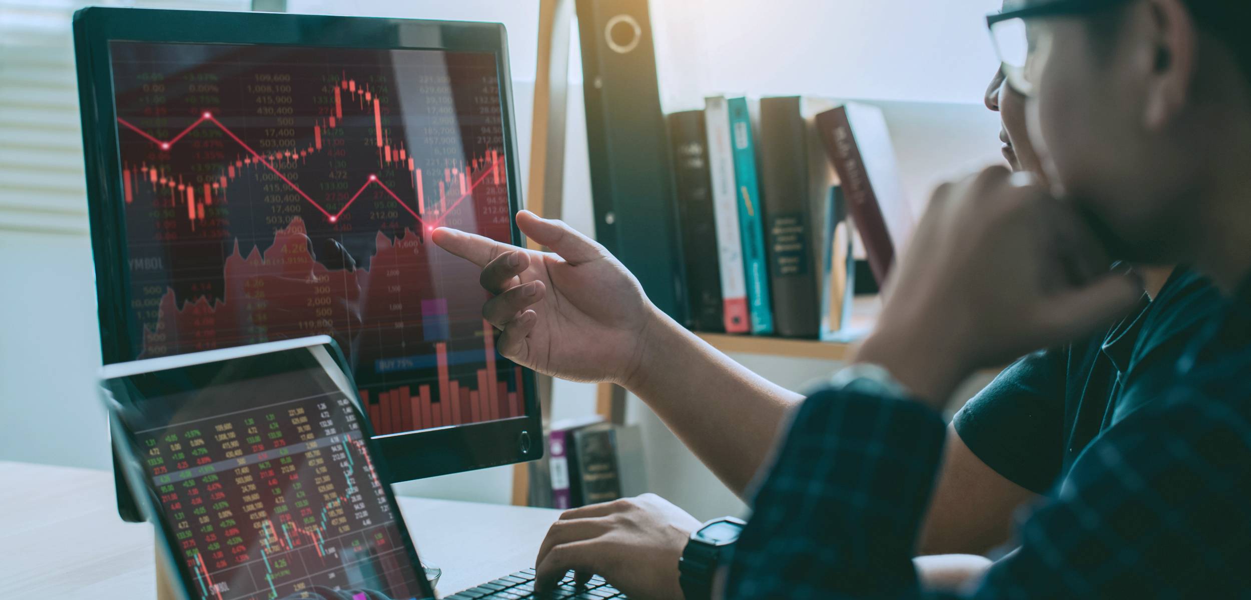male looking at graphs and charts on multiple computer screens.