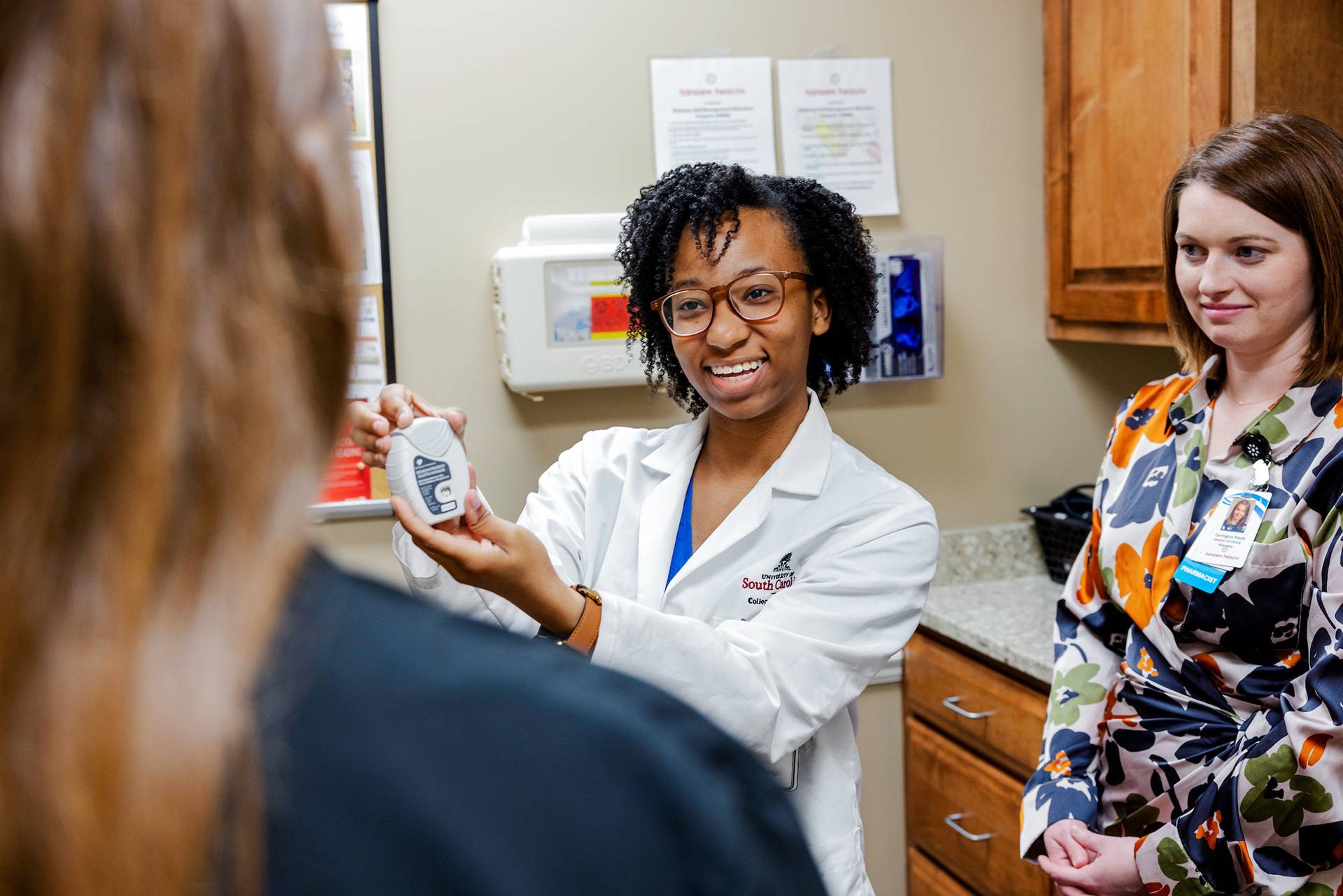 Student demonstrating a medication device to patient