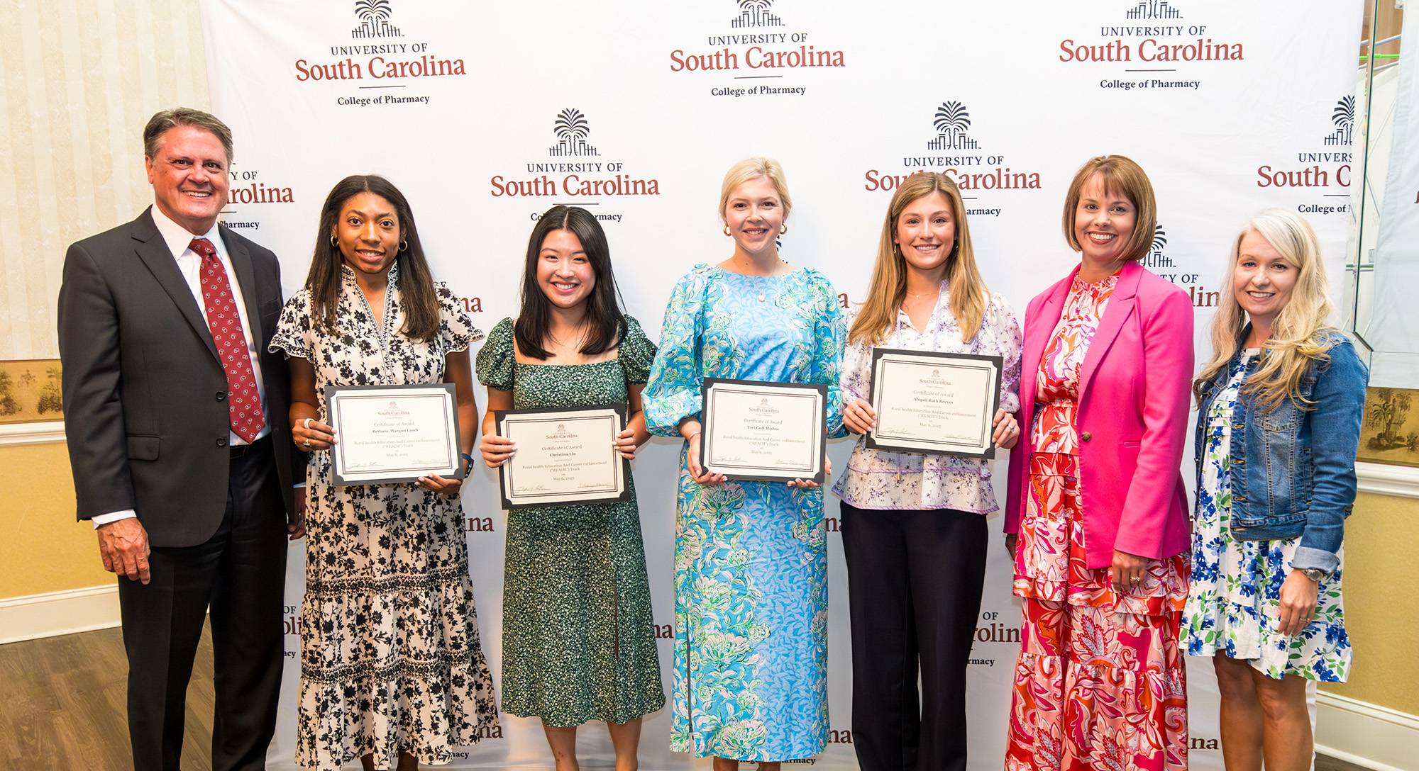 Group of students holding certificates with college administrators