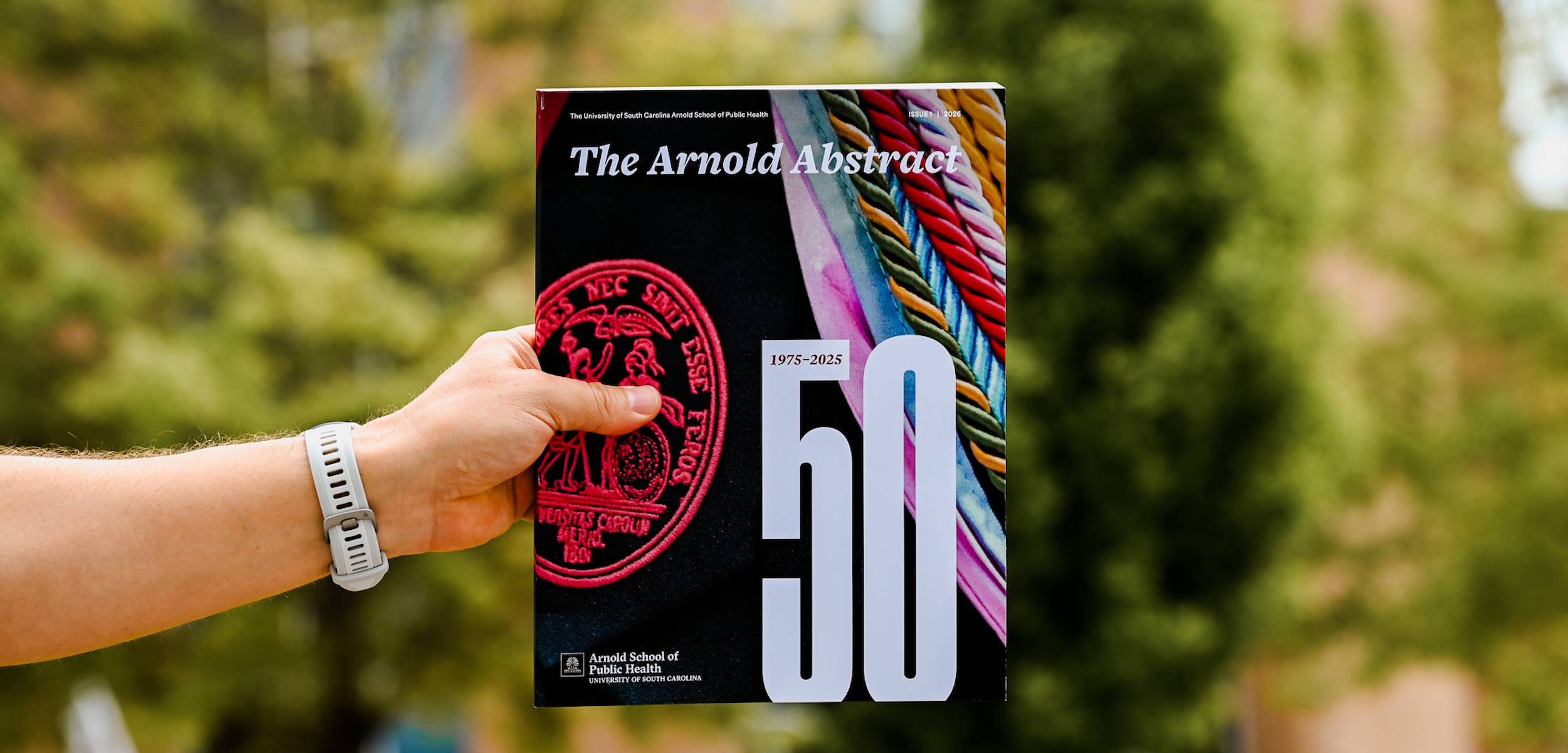 Hand holding out a print copy of the Arnold Abstract