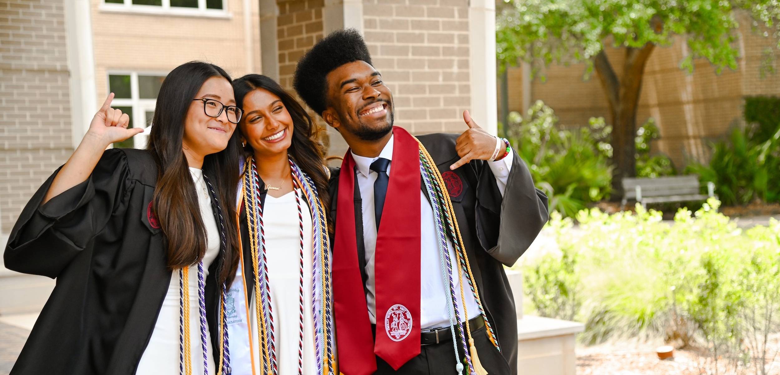 Three students in graduation robes posing